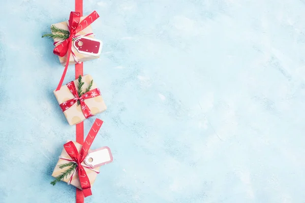 Düz üstten görünüm açık mavi renkli kırmızı şeritler ile üç Noel hediye kutuları Kraft kağıt içinde yatıyordu. Yeni yıl kavramı. Metin alanı