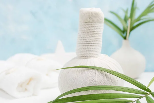Spa background: thai massage bag, cosmetics, towels and palm leaves on blue background. Healthy lifestyle. Text space