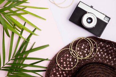 Boho stil kadar sahte: palmiye yaprakları, vintage fotoğraf makinesi, altın bilezik ve plaj şapka pembe ve mor renkli arka plan üzerinde. Seyahat kavramı. Trendy renkler. Metin alanı