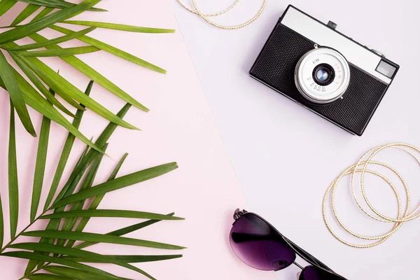 Boho stil kadar sahte: palmiye yaprakları, vintage fotoğraf makinesi, altın bilezik ve pembe ve mor renkli arka plan üzerinde güneş gözlüğü. Seyahat kavramı. Trendy renkler. Metin alanı