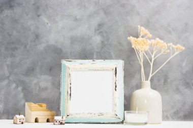 Mavi fotoğraf çerçevesi sahte kare cam vazo içinde Kuru bej bitkiler, raf ahşap evler ile. İskandinav tarzı. Metin alanı