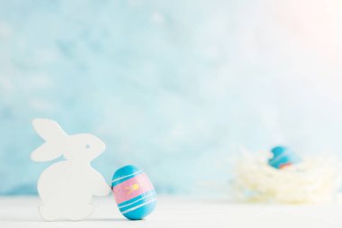 Parlak Paskalya arka plan: mavi duvara paited yumurta ile beyaz ahşap tavşan. Bulanık yuva yumurta arka plan ile. Tatil kavramı. Metin alanı