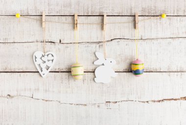 Rustik Paskalya arka plan: Vintage boyalı yumurta beyaz kalp ve bunny sıkı clothespins eski Beyaz ahşap duvar karşı tutun. Tatil kavramı. Metin alanı