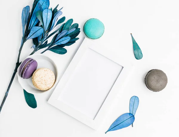 Üstten Görünüm düz boş fotoğraf çerçevesi mockup macarons ve mavi yaprakları ile yatıyordu. Metin alanı