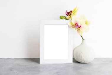Parlak fotoğraf çerçevesi mockup sarı orkide beyaz duvara ile. İç tasarım konsepti. Metin alanı