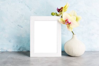 Parlak fotoğraf çerçevesi mockup ışık mavi duvarın karşısında sarı orkide ile. İç tasarım konsepti. Metin alanı