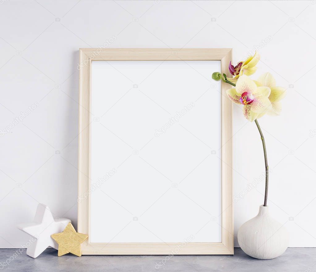 Bright photoframe mockup with yellow orchid against white wall. Interior design concept. Text space