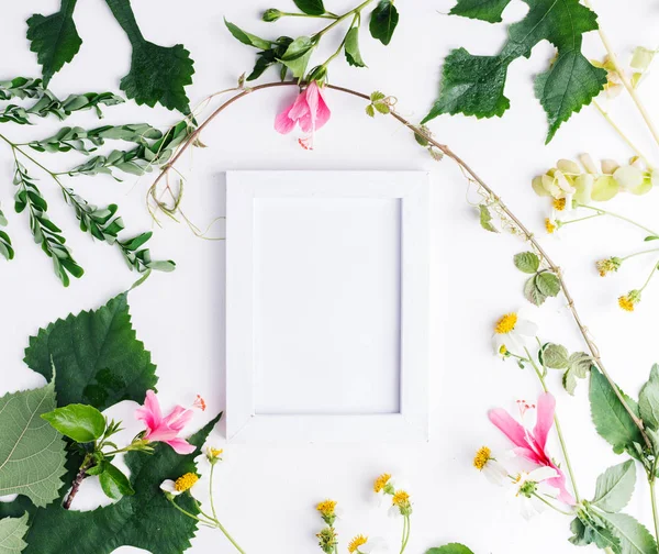 Top view flat lay empty photo frame with summer leaves and daisy flowers mockup. Text space