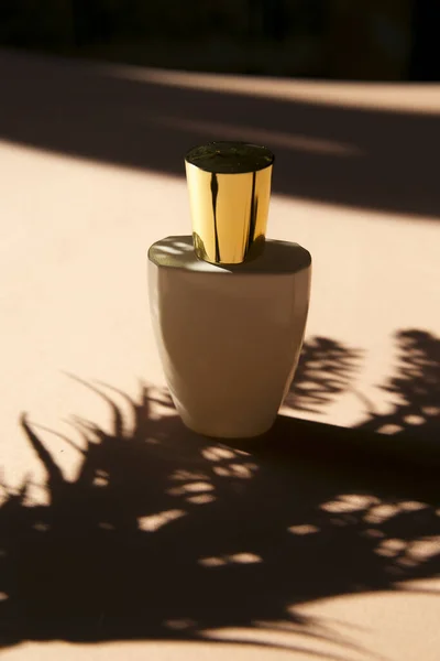 little bottle with perfume and  shadow of leaves in sunshine, close view