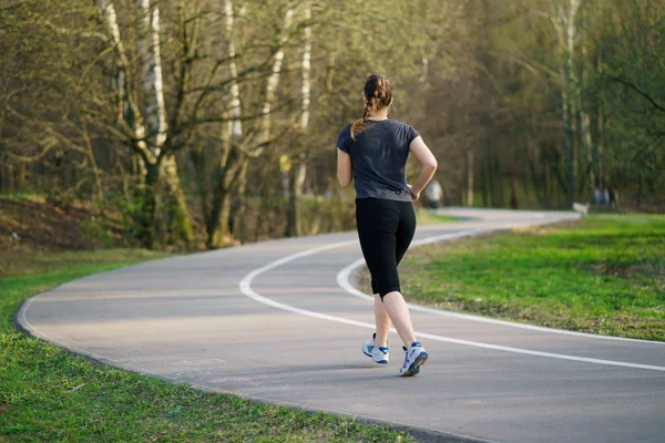 Running woman in park in spring training, girl in sporty running clothes.