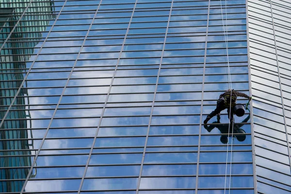 Industrial mountaineering worker wash windows of a high-rise building