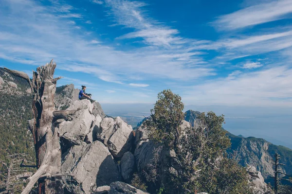 Uma jovem viajante se senta no topo da montanha — Fotografia de Stock