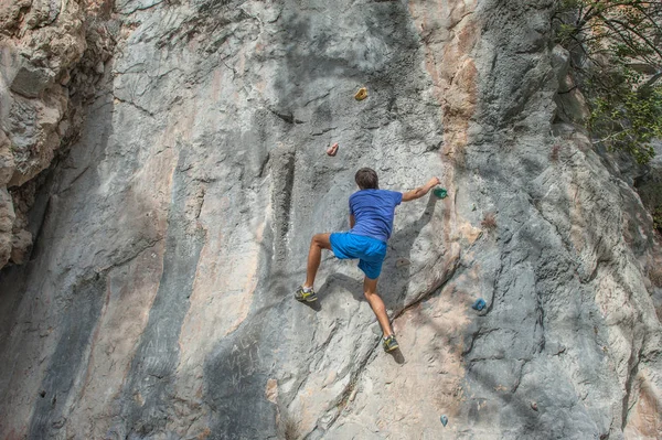 Young athletic man free climbing