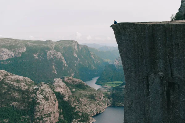 Homem sentado à beira de Preykestalen, Noruega — Fotografia de Stock