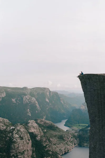 Homem sentado à beira de Preykestalen, Noruega — Fotografia de Stock