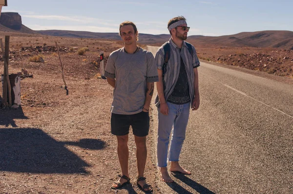 Twee vrienden van toeristen op de weg in de woestijn — Stockfoto