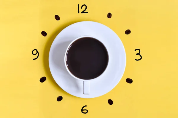 Bir fincan kahve seyretmek yüz 6 AM (18: 00) ile sarı bir arka plan (tablo). Kahve içmek için zaman. Kahve çekirdekleri ile