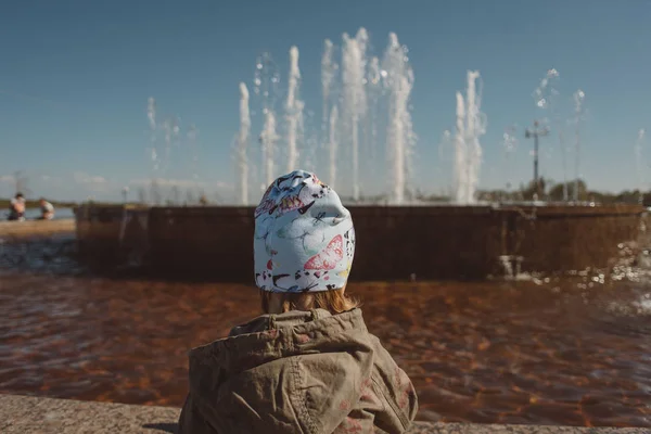 Дівчина в капелюсі дивиться на фонтан — стокове фото