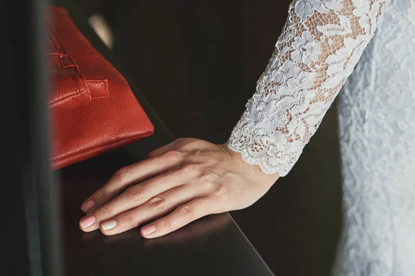 La mano della sposa in un vestito con pizzo sul tavolo — Foto Stock