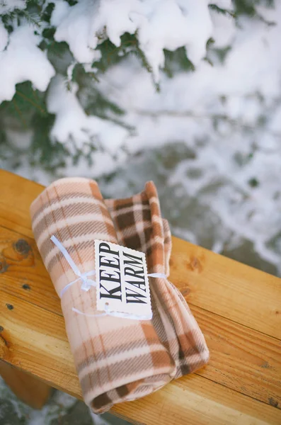 Marron plaid sur un banc en bois avec un signe garder au chaud Images De Stock Libres De Droits