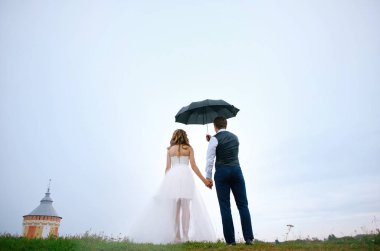 Gelin ve damat bir şemsiye ve gökyüzü altında