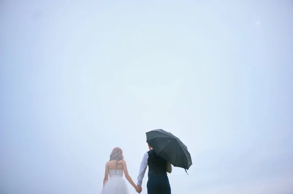 La novia y el novio bajo un paraguas y el cielo —  Fotos de Stock
