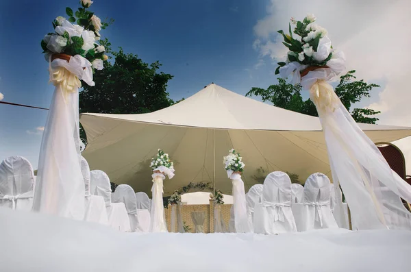 Auvent de mariage blanc en été avec chaises en tissu blanc, décoration de fleurs, roses blanches et verdure, enregistrement de sortie Photos De Stock Libres De Droits