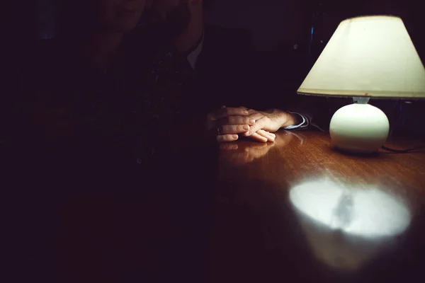 Mains d'homme et de femme sur une table en bois marron à la lumière d'une lampe de bureau dans une pièce sombre Images De Stock Libres De Droits