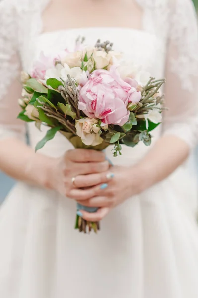 Brautstrauß mit weißer Spitzenschleife, weißen Rosen und Pfingstrosen und Grüntönen in den Händen der Braut, Nahaufnahme — Stockfoto