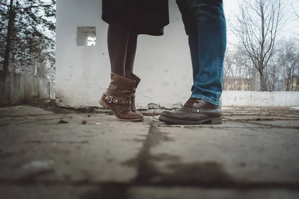 Jambes d'une jeune fille avec des bottes brunes et un homme en jean bleu et des bottes au printemps dans la rue gros plan des amateurs de pieds — Photo