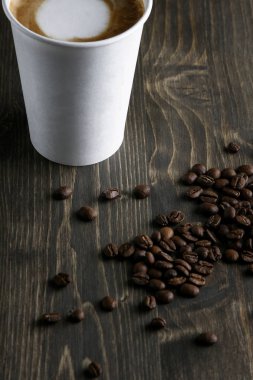 Ahşap arka plan üzerinde beyaz bir fincan kahve içmek