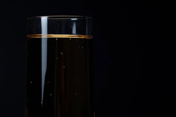 Perto de uma taça cheia de champanhe sobre preto — Fotografia de Stock