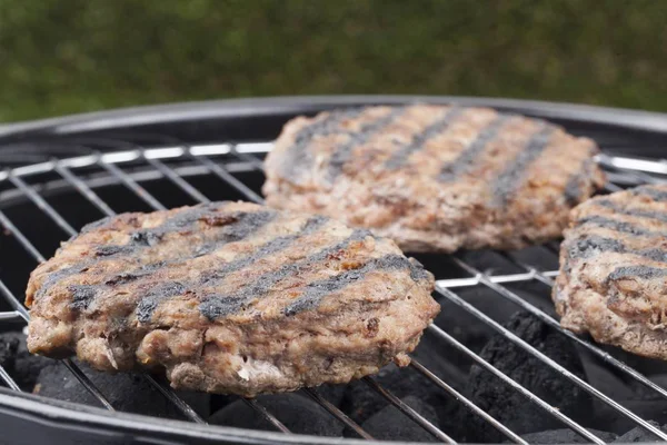 Hamburguesas asando a la parrilla de carbón — Foto de Stock