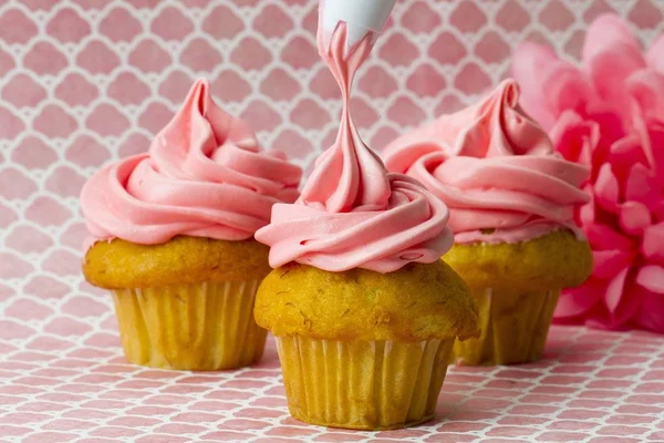 Icing yang diterapkan untuk tiga cupcakes di pink — Stok Foto