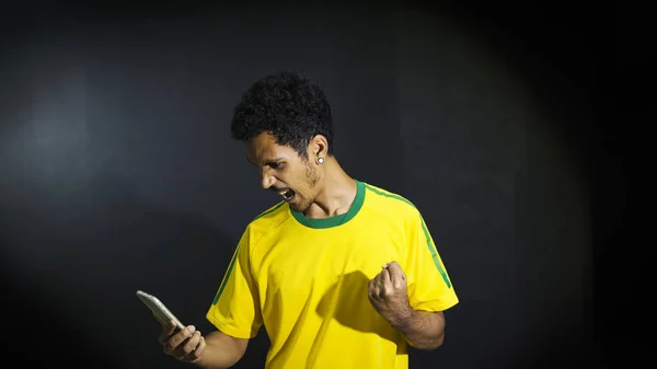 Male Athlete Fan Yellow Uniform Looking Cell Phone Blac — Stock Photo, Image