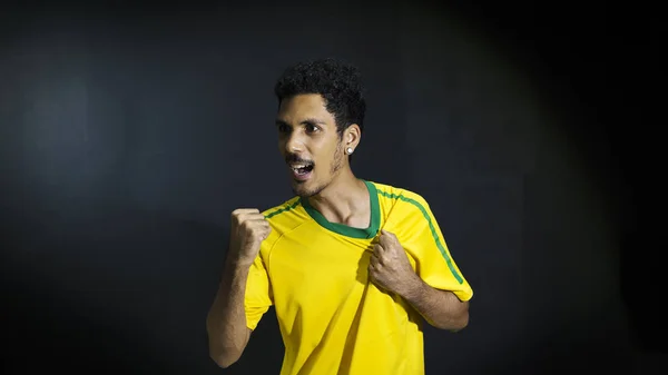 Male athlete or fan in yellow uniform celebrating on black backg — Stock Photo, Image