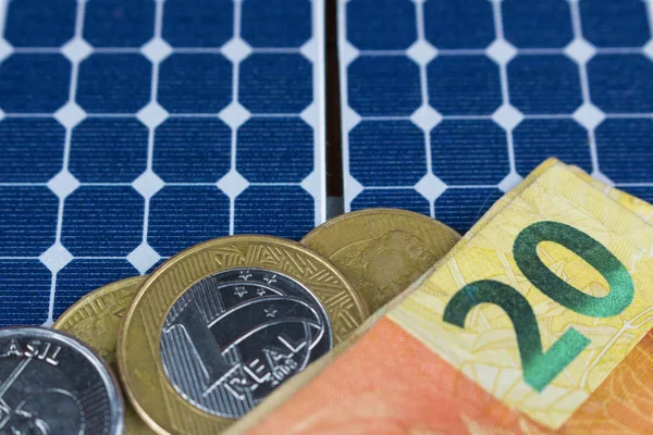 Solar panel with 20 bill of Brazilian money and coins.