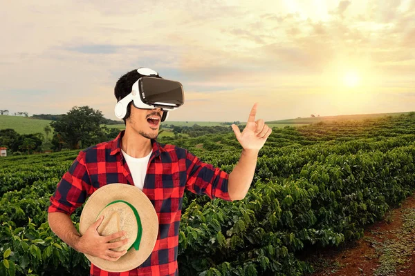 Farmer with hat and virtual reality glasses on coffee plantation