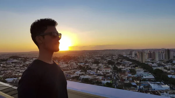 Silueta de un hombre en la parte superior de un edificio. Puesta de sol en la ciudad en — Foto de Stock