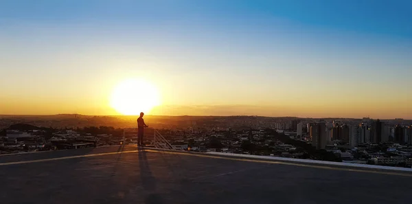 Bir adam bir binanın üstüne silüeti. Şehirde on Sunset — Stok fotoğraf