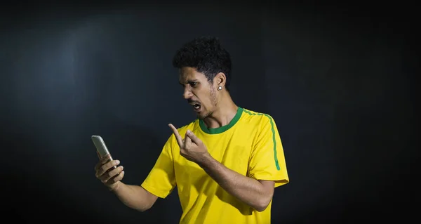 Manliga idrottare eller fläkt i gult enhetliga söker mobiltelefon på blac — Stockfoto