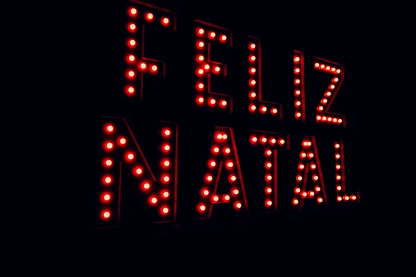 Feliz Natal escrito em português sobre neon vermelho luz preto fundo — Fotografia de Stock