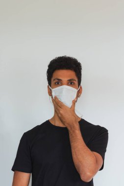 Koronavirüs maskesi takan yetişkin bir adam beyaza izole edilmiş olduğunu düşünüyor..