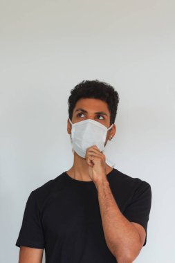 Koronavirüs maskesi takan yetişkin bir adam beyaza izole edilmiş olduğunu düşünüyor..