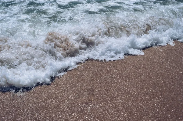Sıcak, güneşli bir günde deniz köpüğü ve kum.