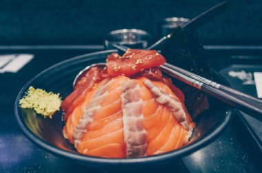 Taze somon kaplı taze pirinç tabağı ve wasabi soslu ton balığı parçaları ve Norveç yosunu.