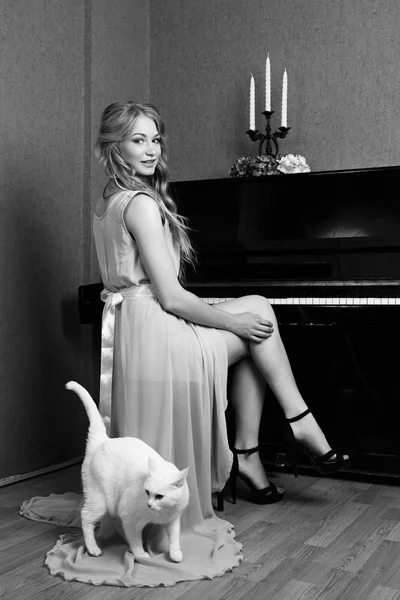 Sexy linda loira menina no vestido tocando piano com um gato — Fotografia de Stock