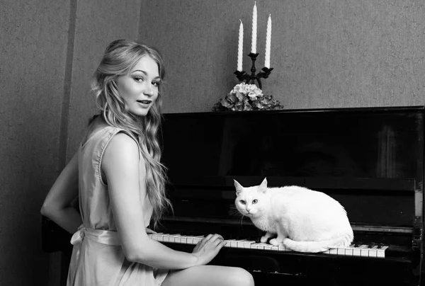 Sexy krásná blond dívka v šatech, hrát na klavír s kočkou — Stock fotografie