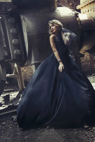Блондинка в черном платье на старой заброшенной фабрике. steampunk — стоковое фото