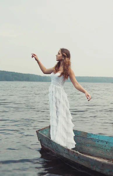 Álmodozó titokzatos szőke lány fehér ruhát egy régi hajó a tavon — Stock Fotó